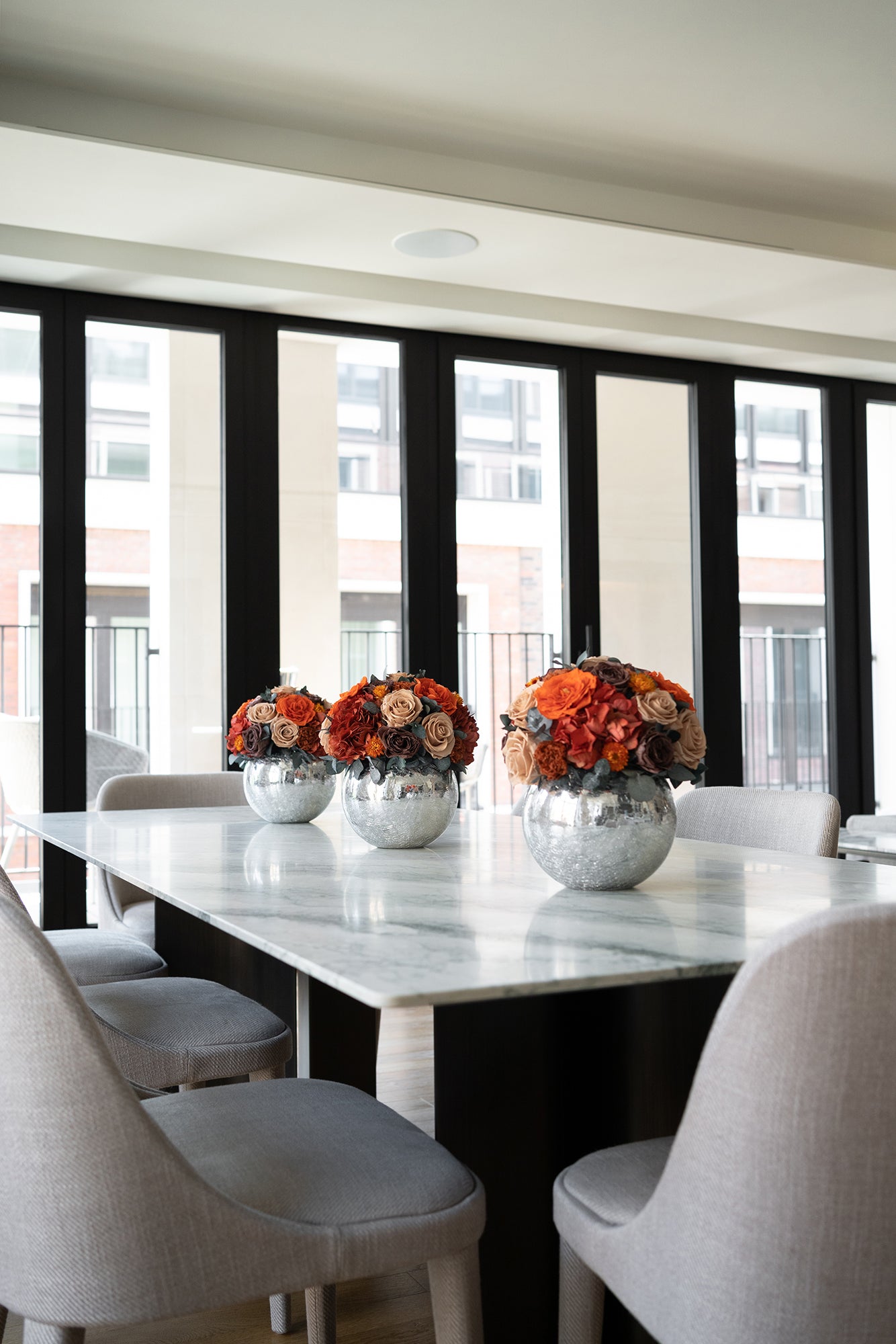 Modern dining room with marble table and preserved mixed floral centerpieces.
