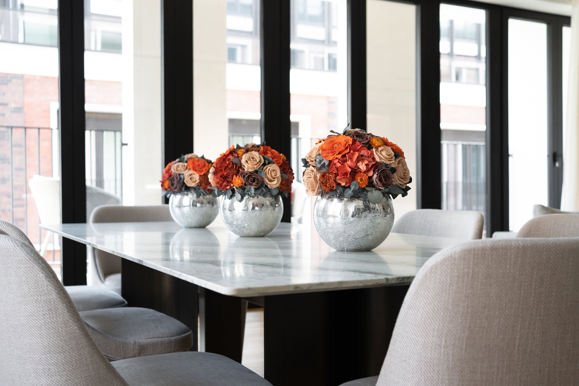 Modern dining room with marble table and preserved mixed floral centerpieces.