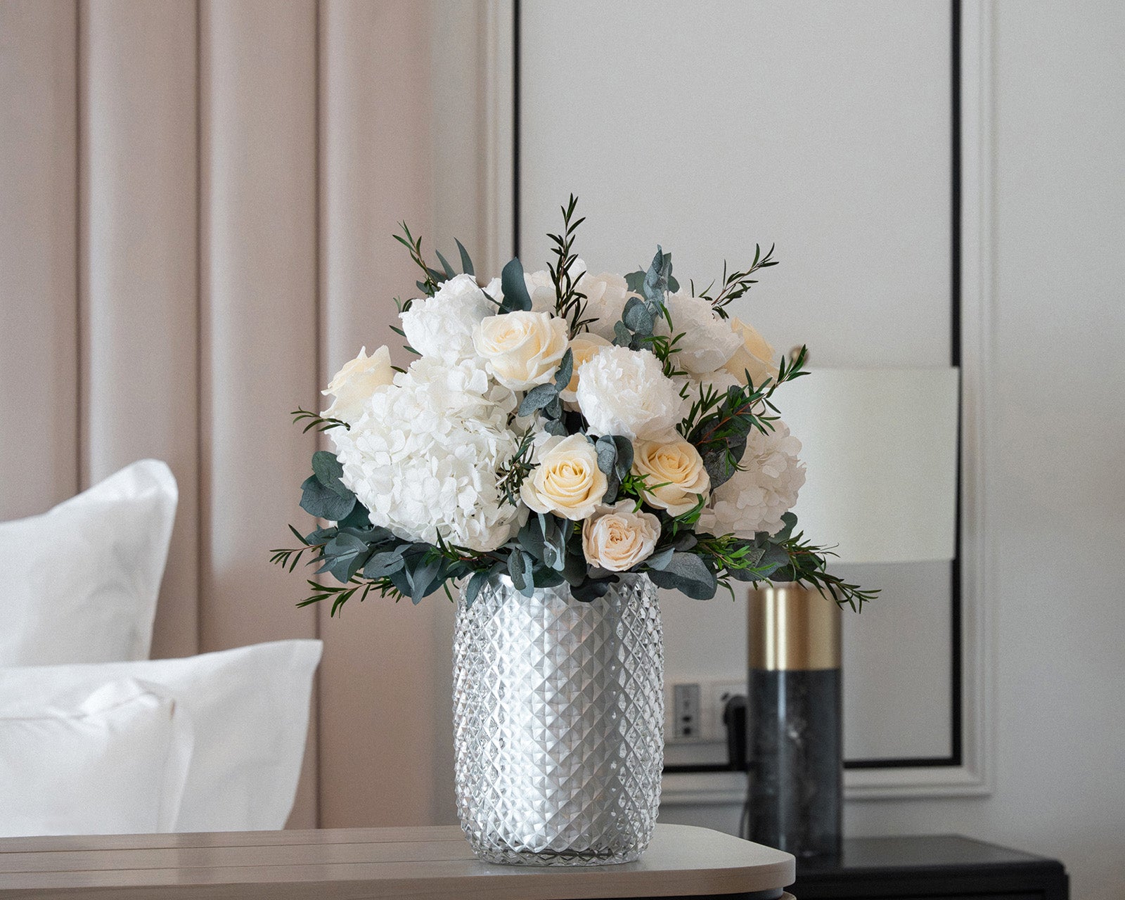 Preserved roses, peonies and hydrangeas arrangement in glass vase in a hospitality setting