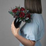 A preserved burgundy rose arrangement with lavender in black vase