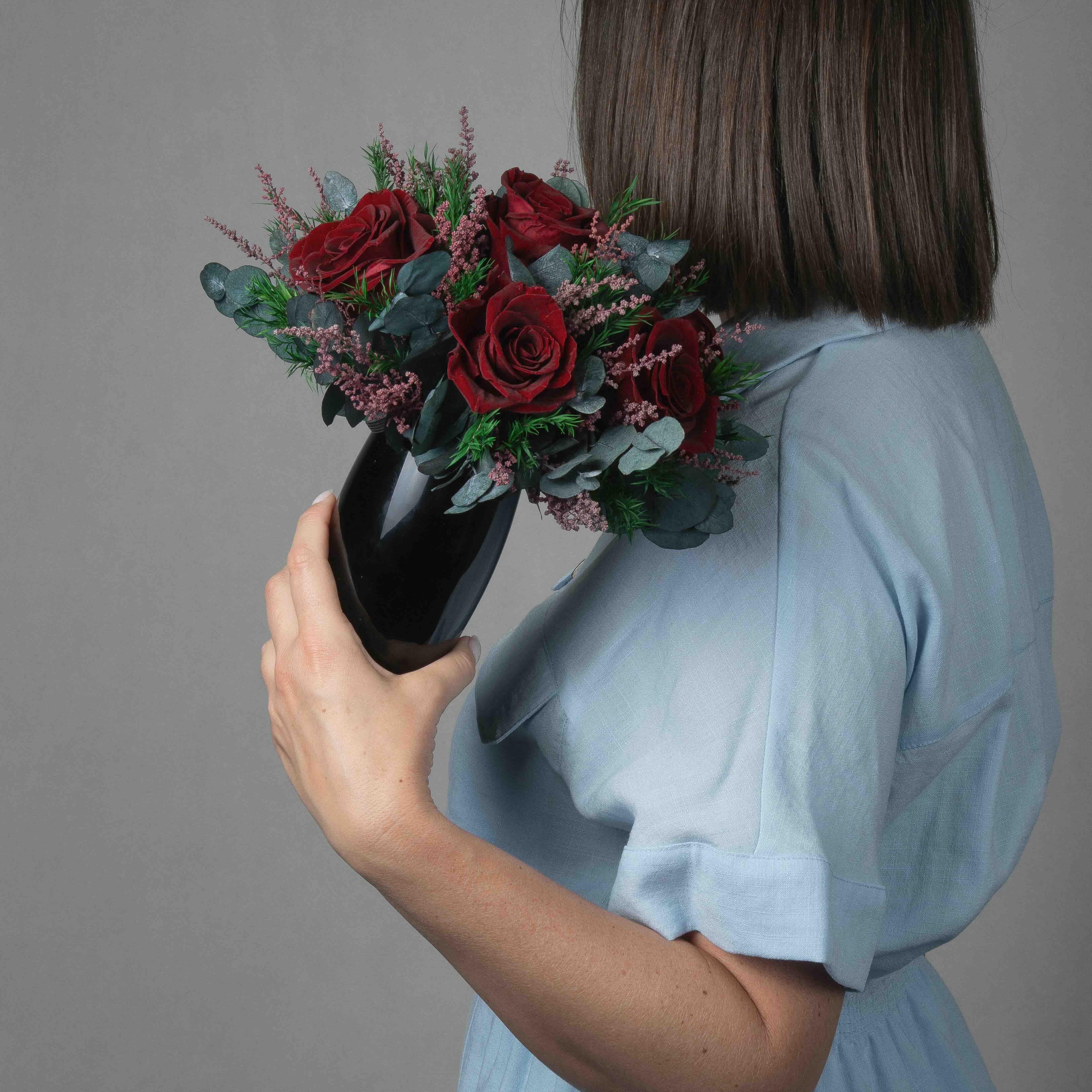 A preserved burgundy rose arrangement with lavender in black vase