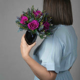 A preserved magenta rose arrangement with lavender in black vase