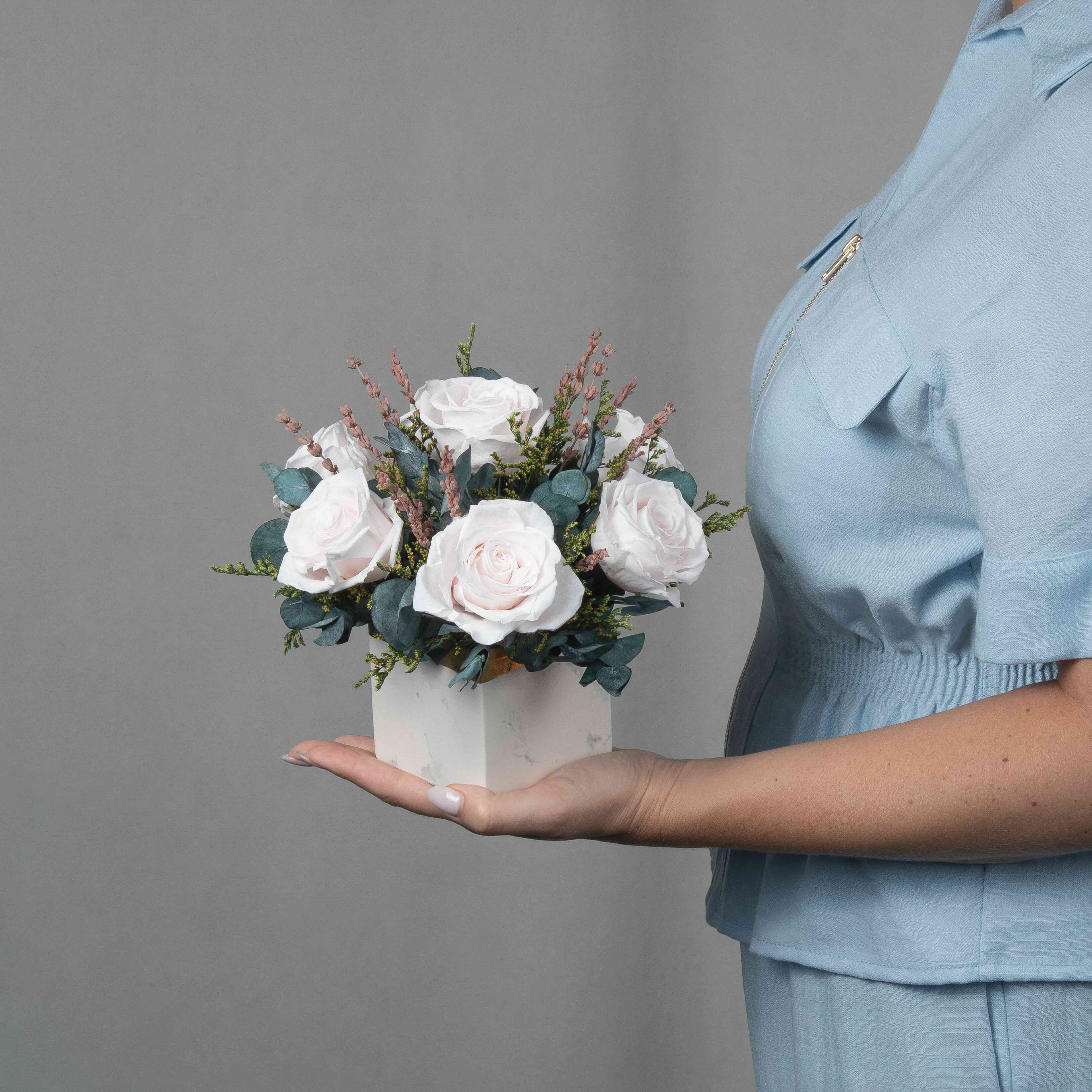 A preserved blush rose arrangement in marble vase