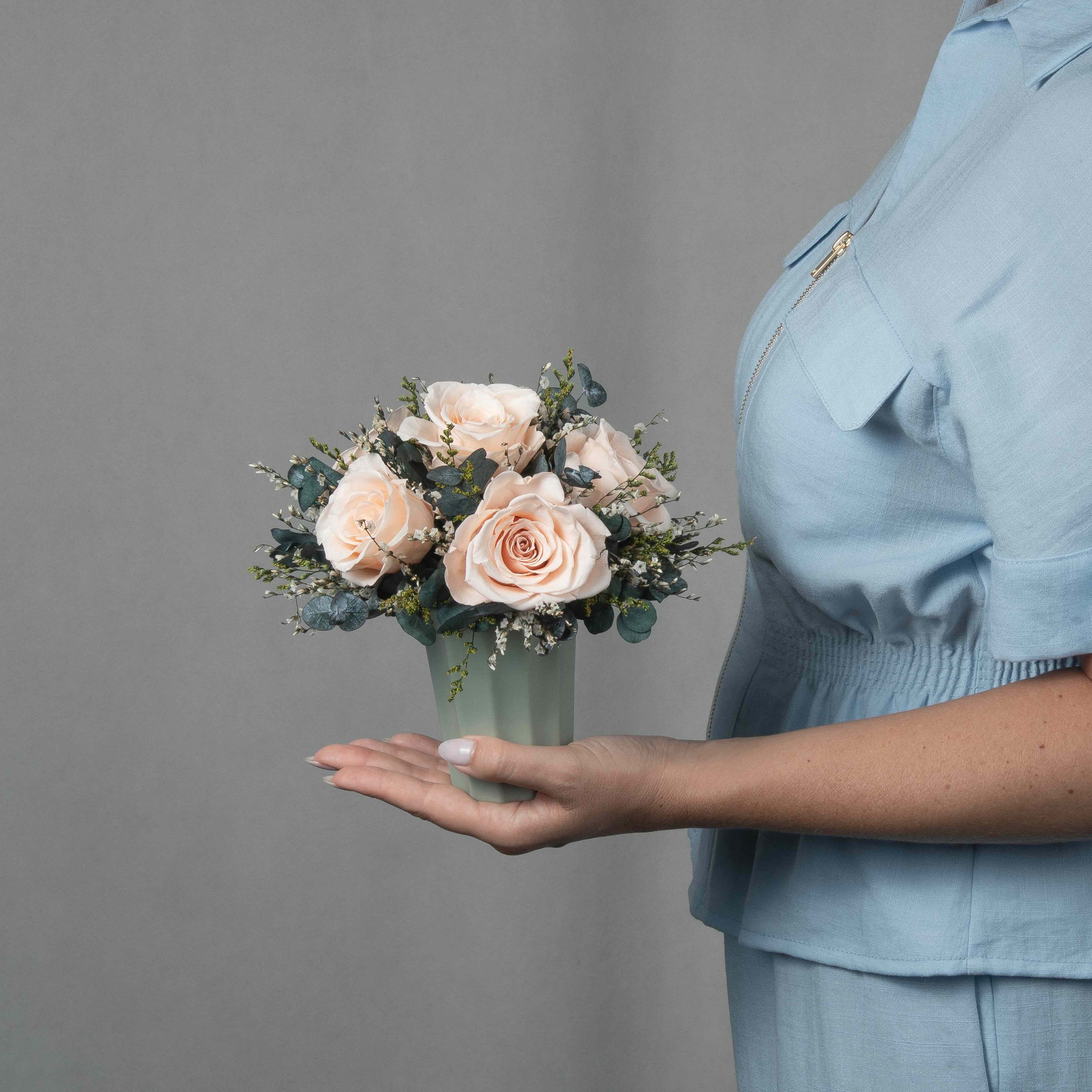 A preserved peach rose arrangement in green vase