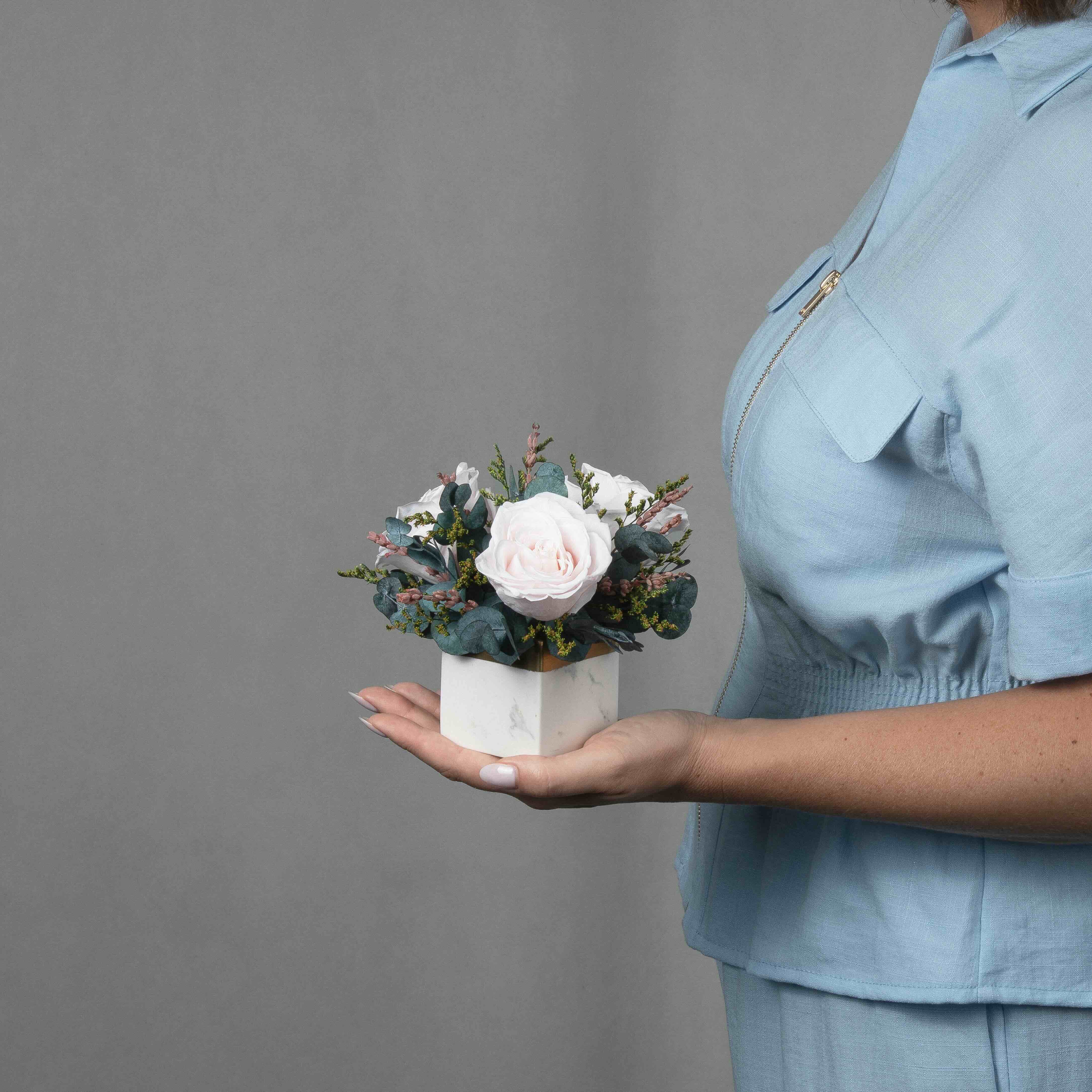 A preserved blush rose arrangement in marble vase