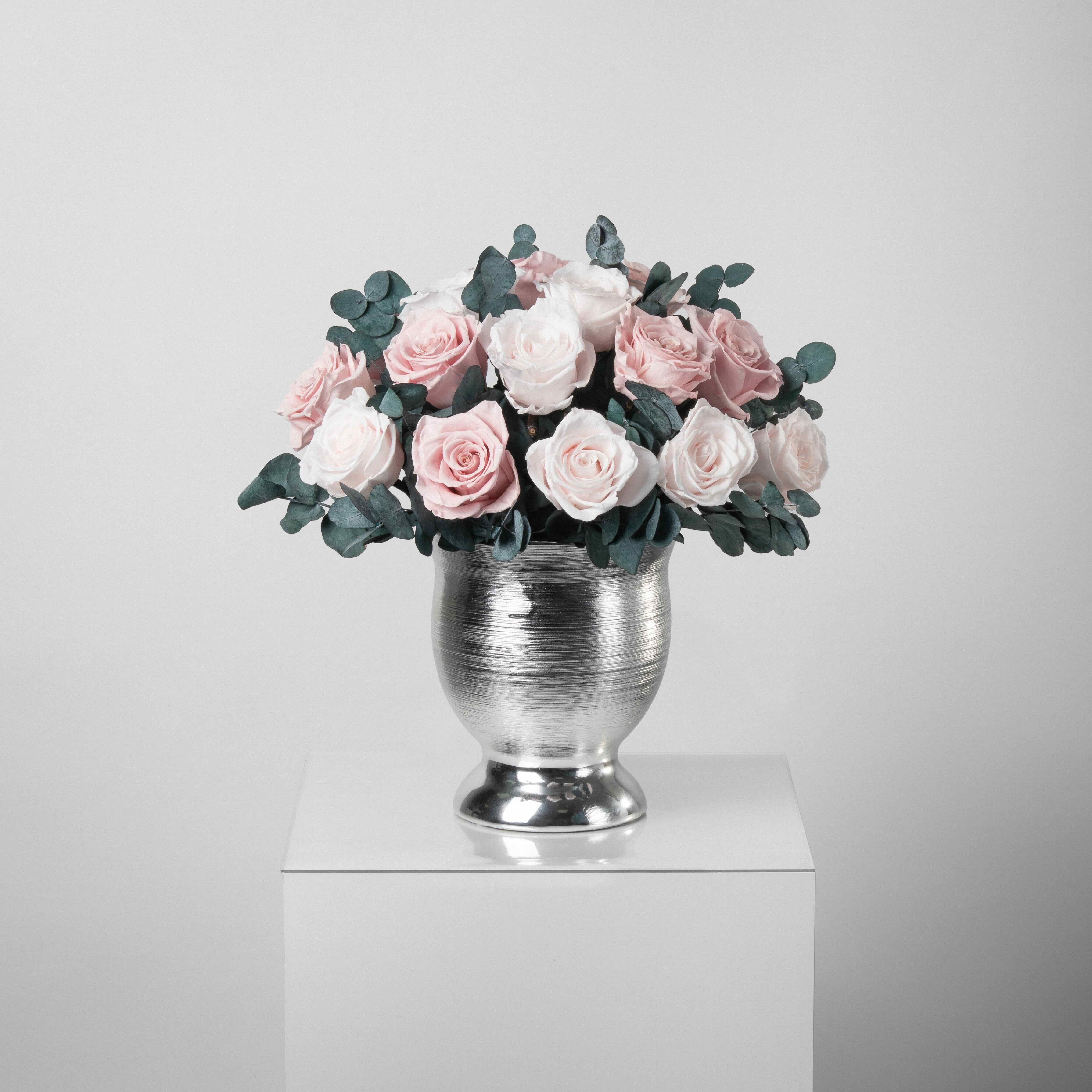 A preserved blush rose dome with foliage in silver vase
