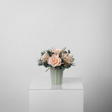 A preserved peach rose arrangement in green vase