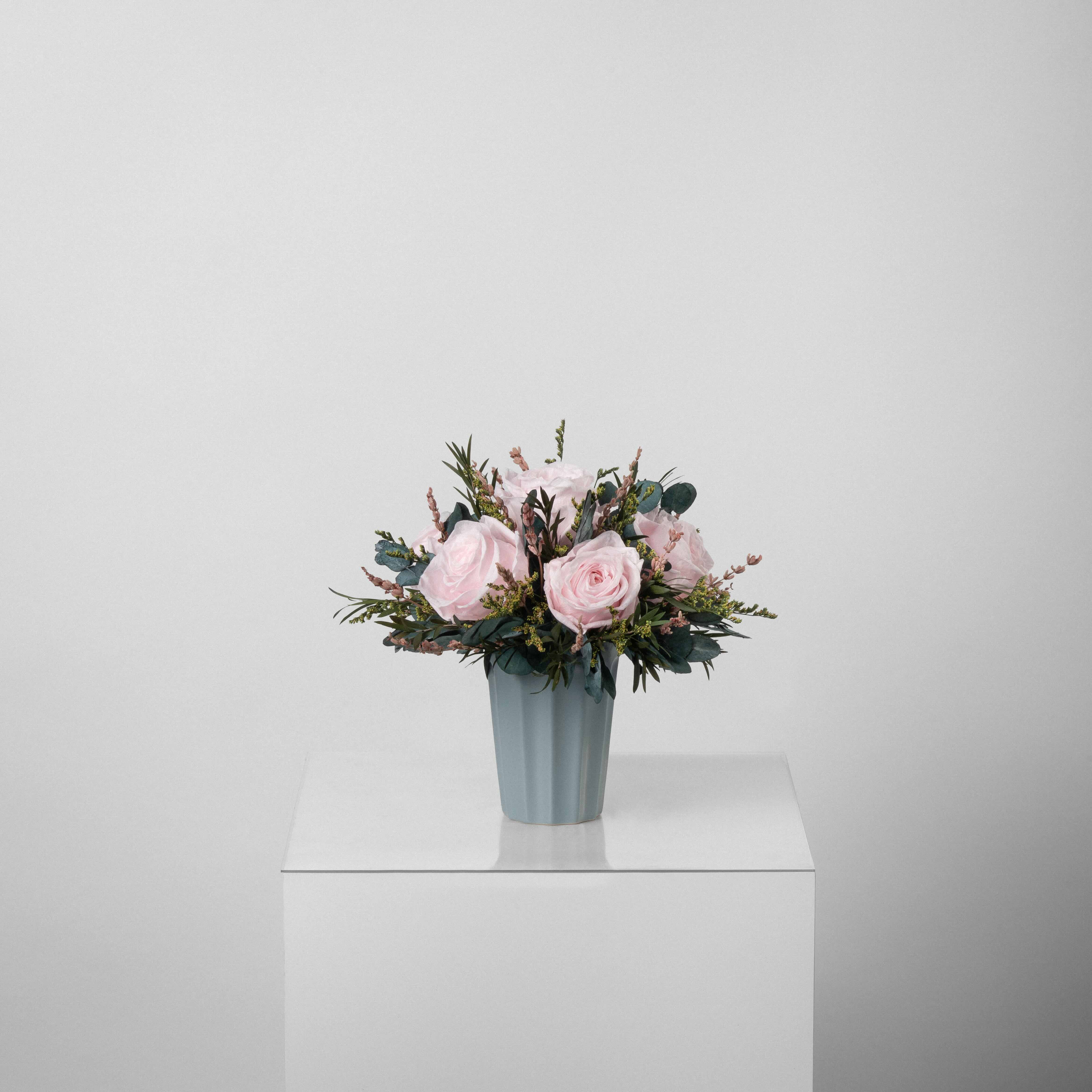 A preserved pink rose arrangement in green vase
