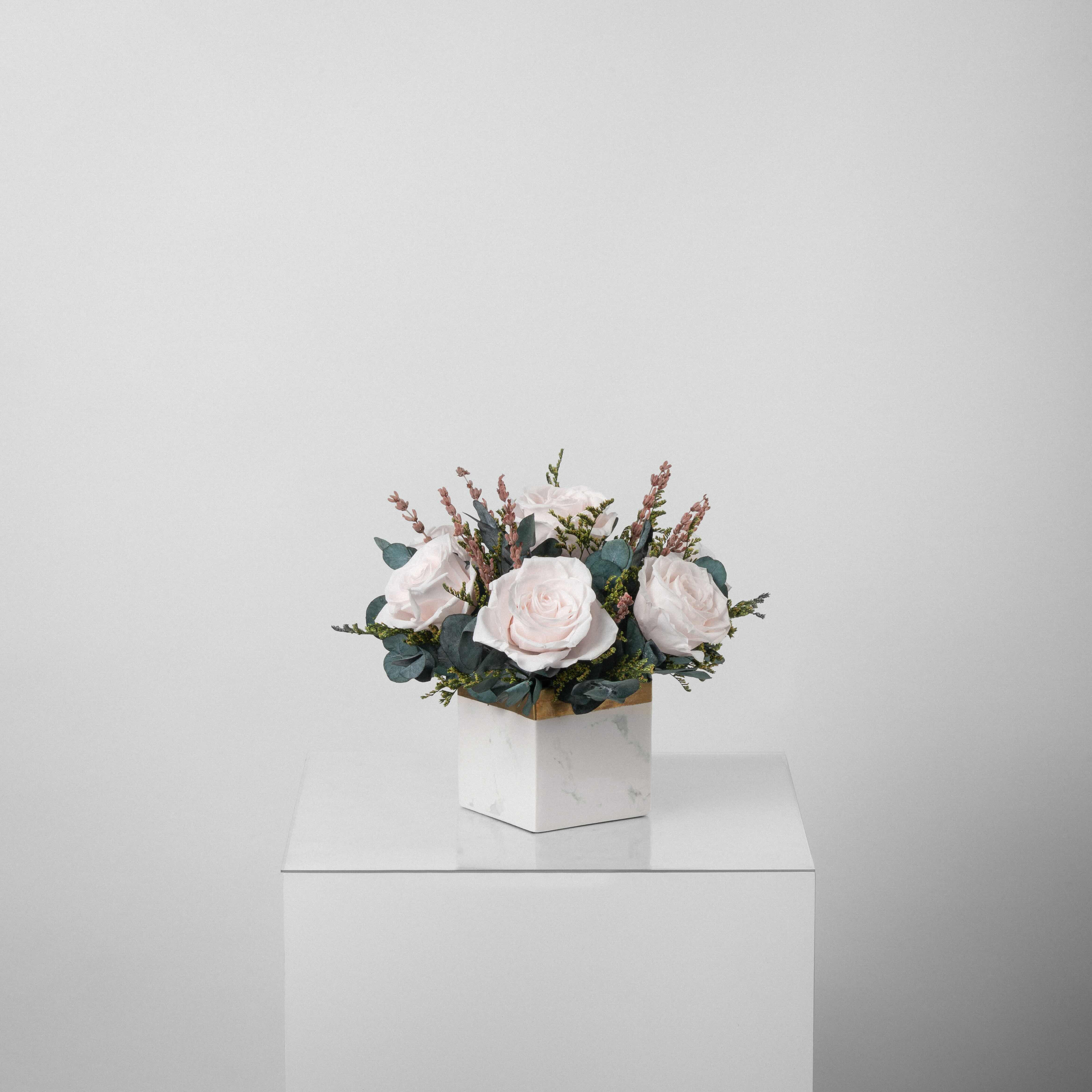 A preserved blush rose arrangement in marble vase