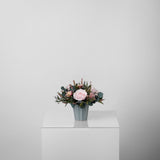 A preserved rose arrangement with preserved foliage in blue vase