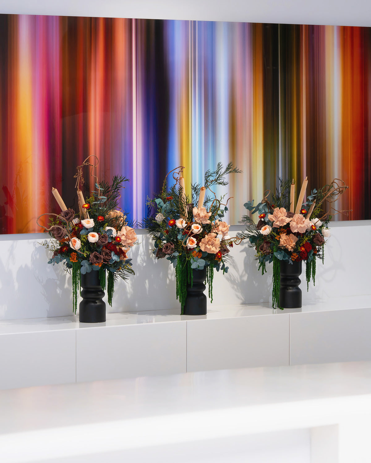 Three preserved floral arrangements in black vases displayed in an office space.