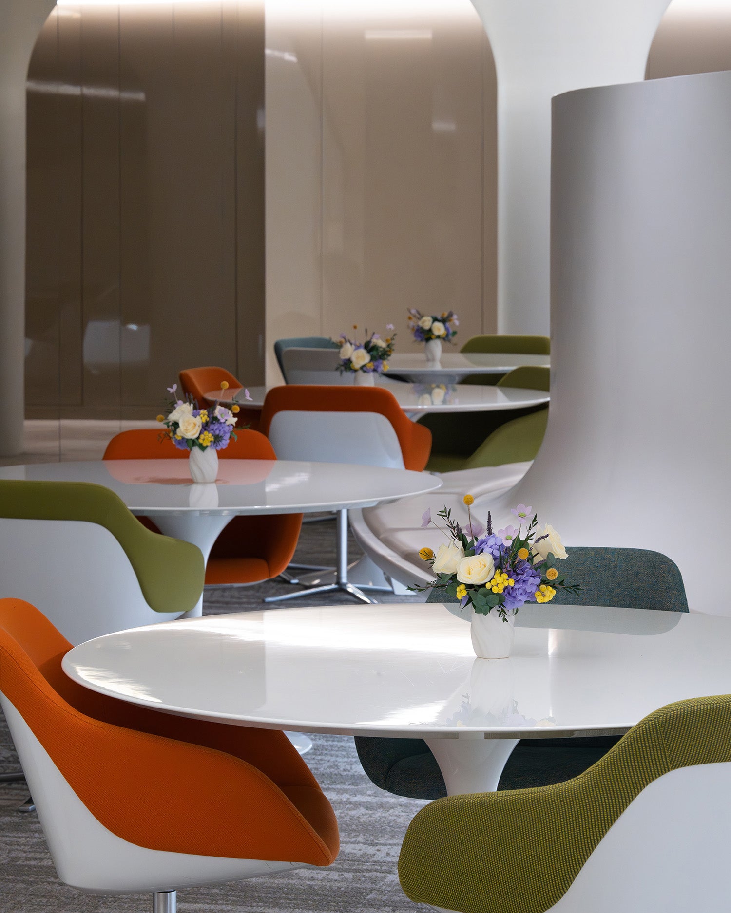Preserved roses and hydrangeas in lilac and yellow colour on office tables

