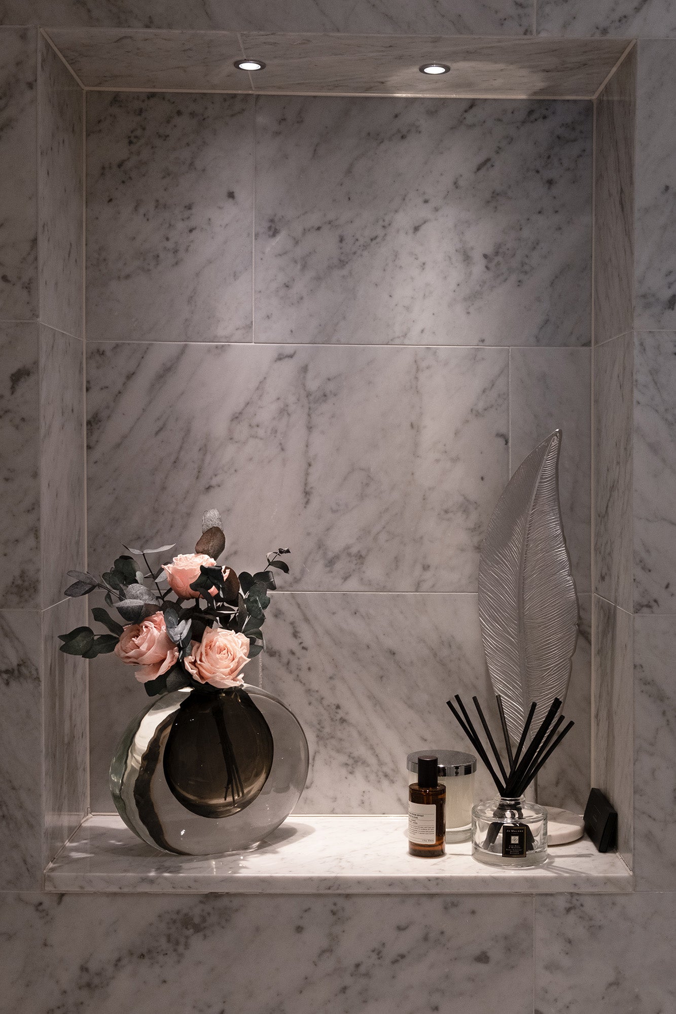 A decorative arrangement featuring preserved roses and preserved eucalyptus on a marble shelf