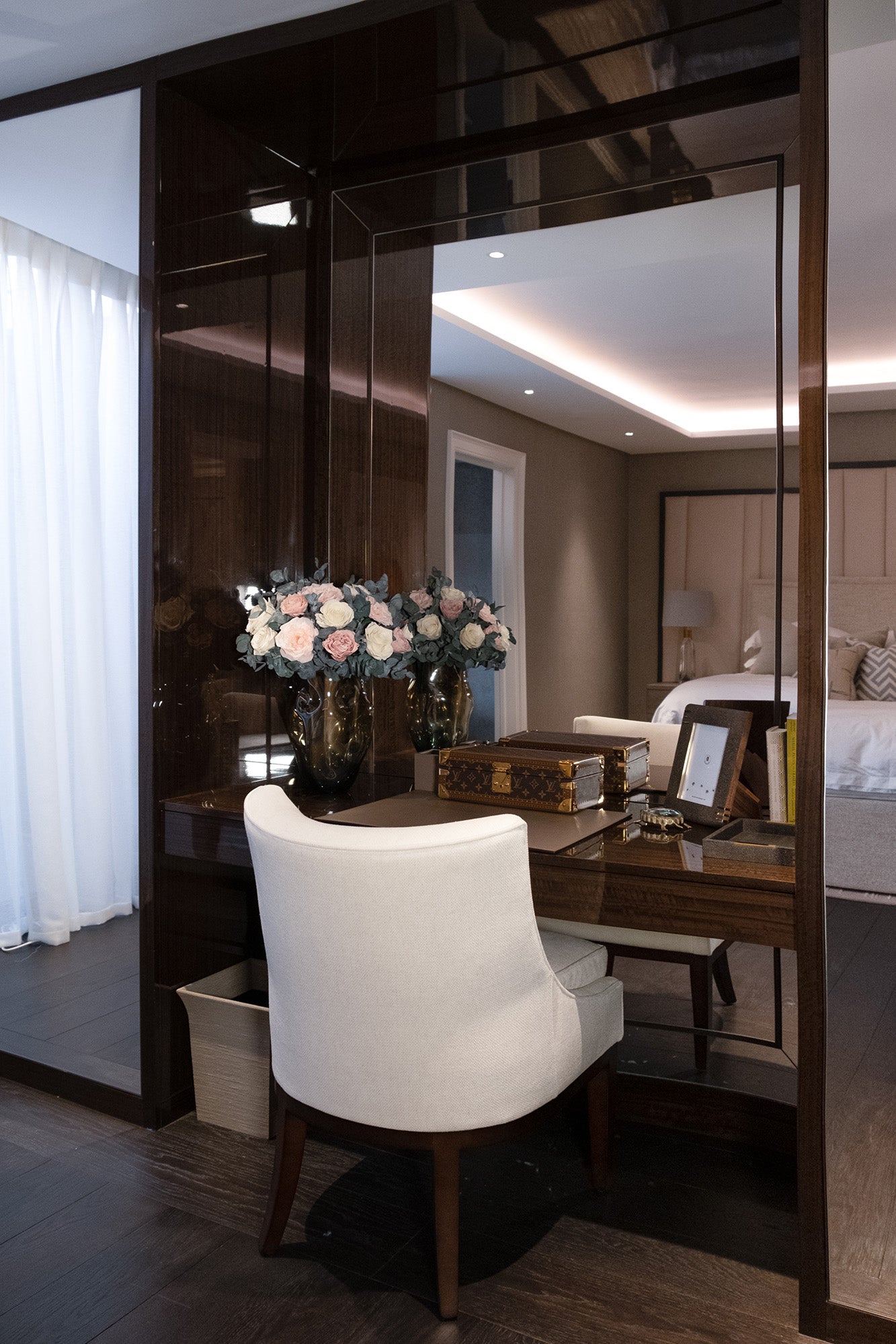 Preserved mixed flowers arranged in a vases on a table with a bedroom in the background