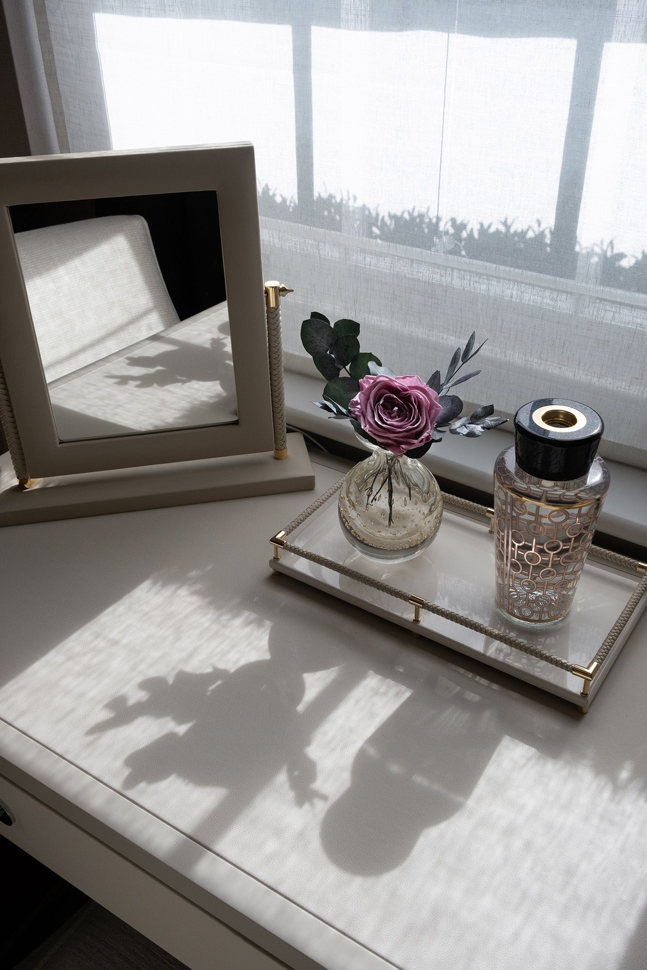 Decorative table with a preserved roses and gardenias arrangement next to a bathtub in a bathroom setting.
