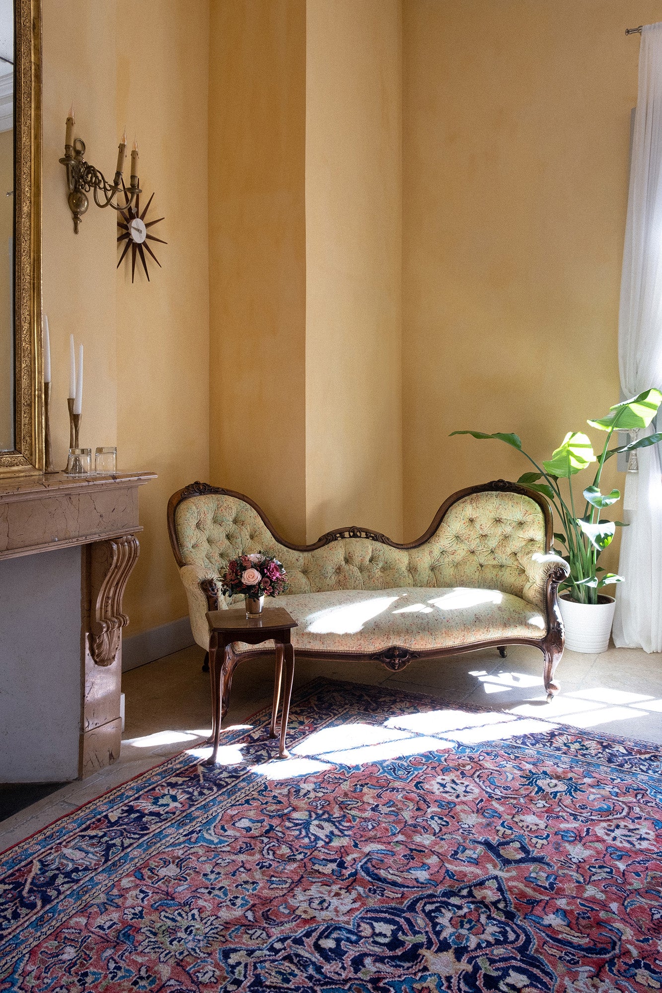 Vintage room with a preserved mixed flower arrangement, ornate sofa, and patterned rug.