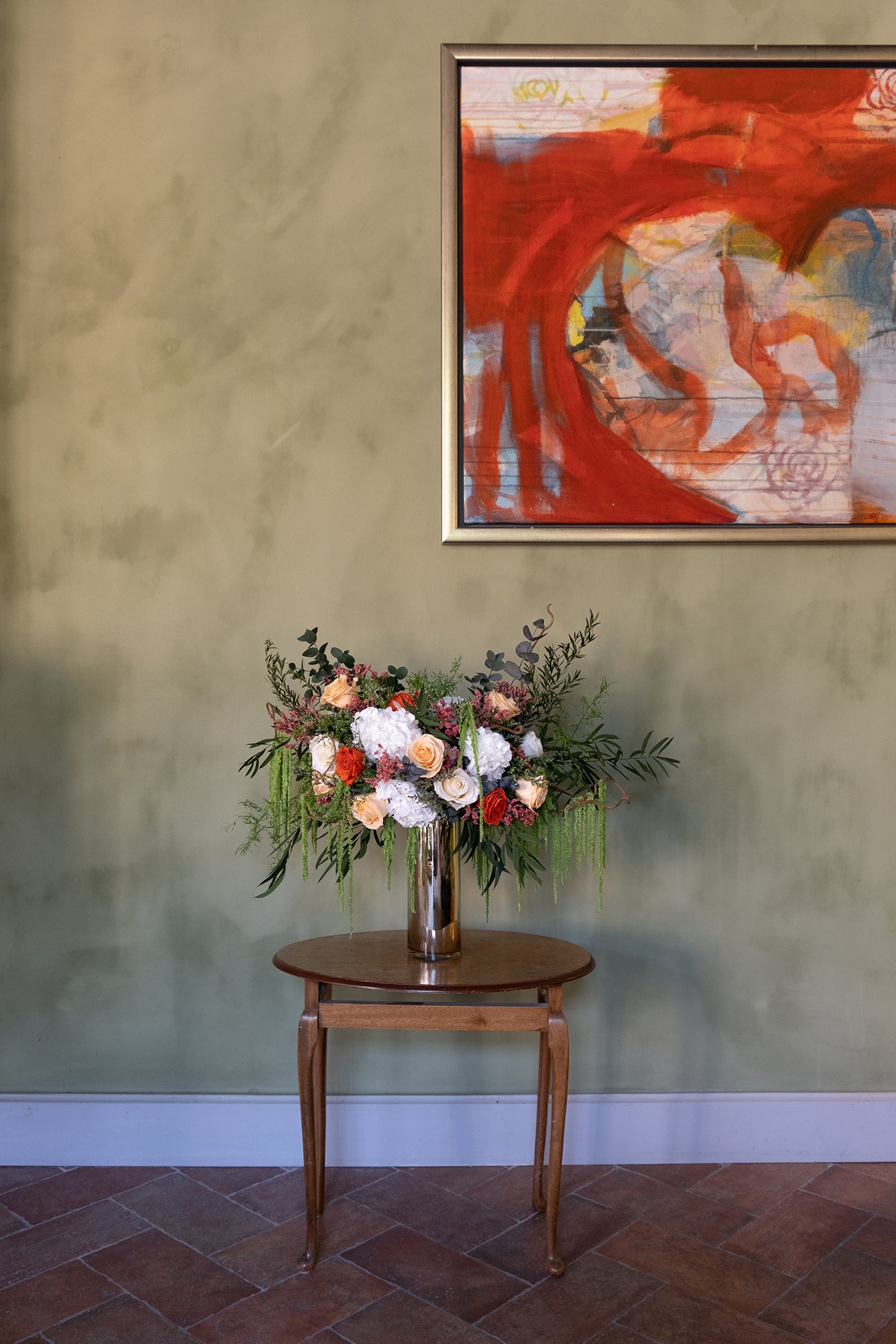 Preserved mixed flower arrangement on a wooden table with abstract art on the wall.