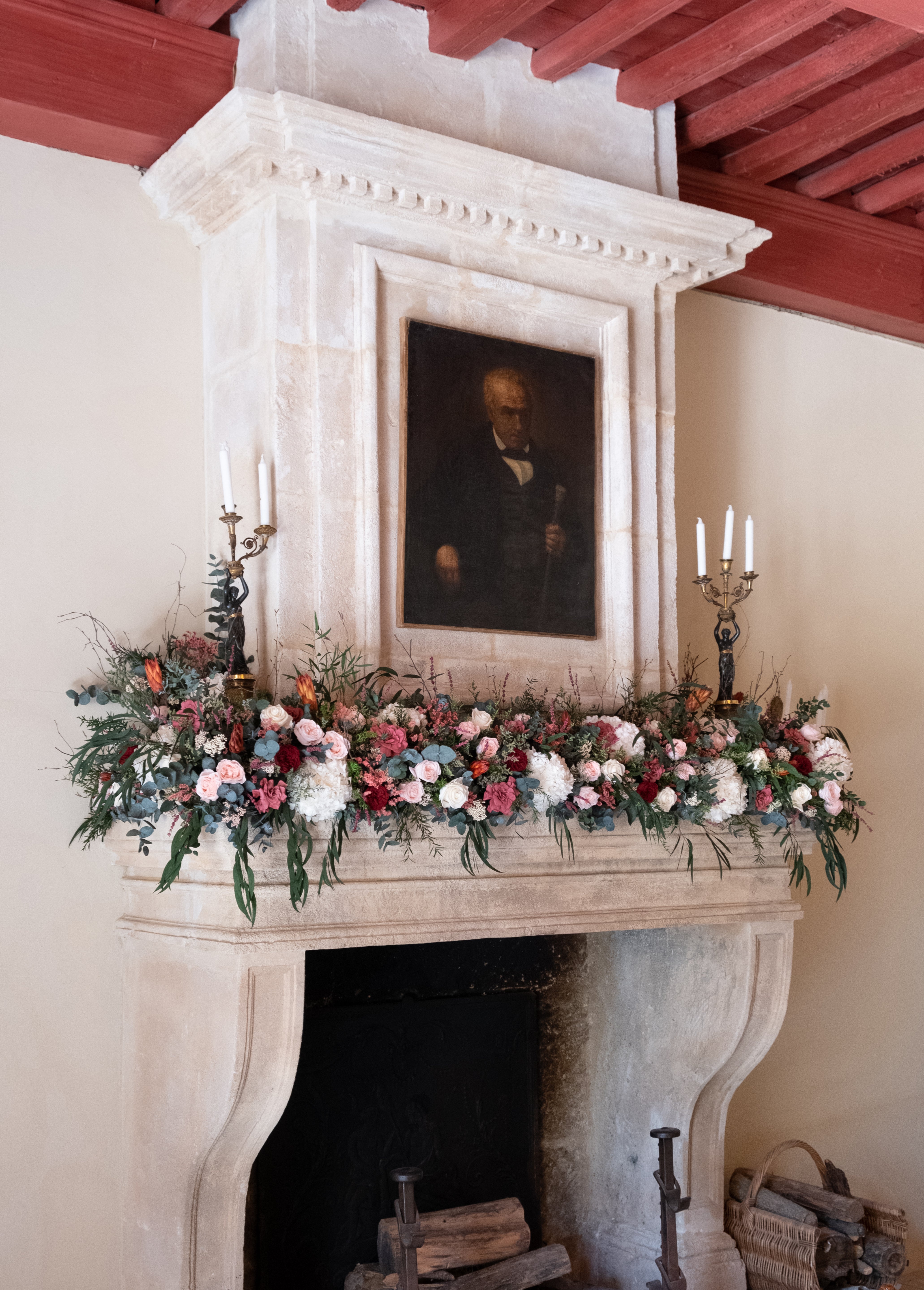 Preserved mixed floral arrangement on a fireplace mantel with a portrait above