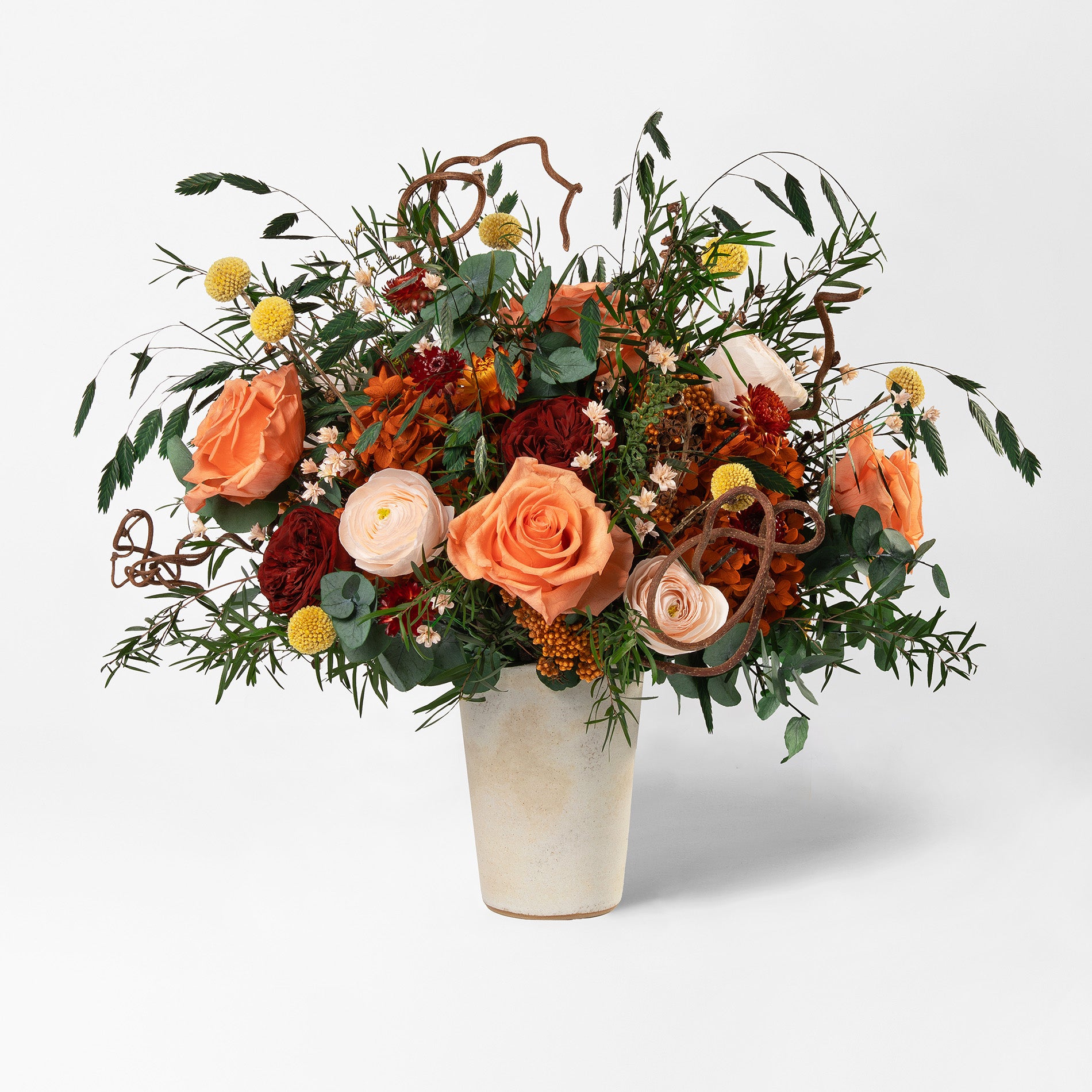 Preserved floral arrangement with orange, red, peach, and filler flowers in a ceramic handmade vase 