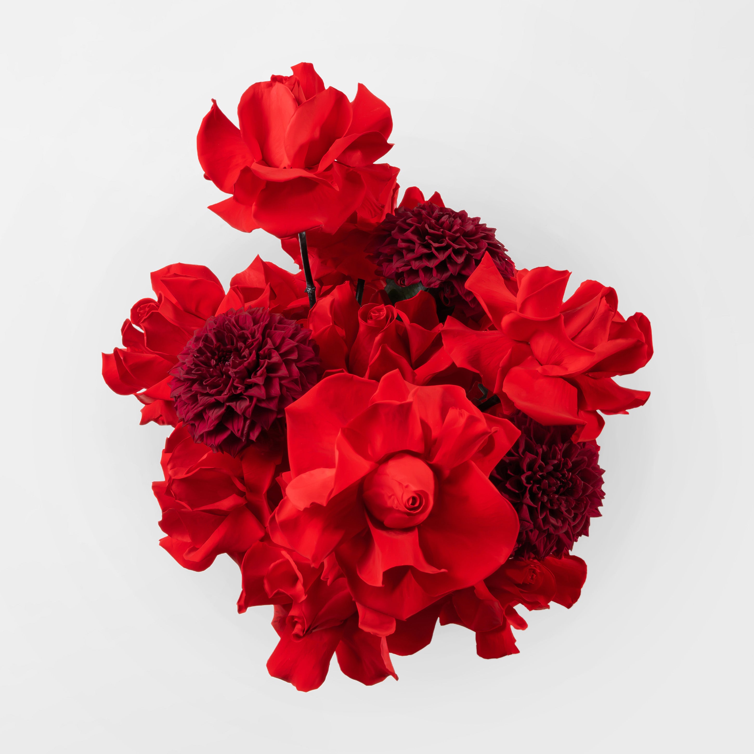 Preserved red reflexed roses and red dahlia in a gold glass vase