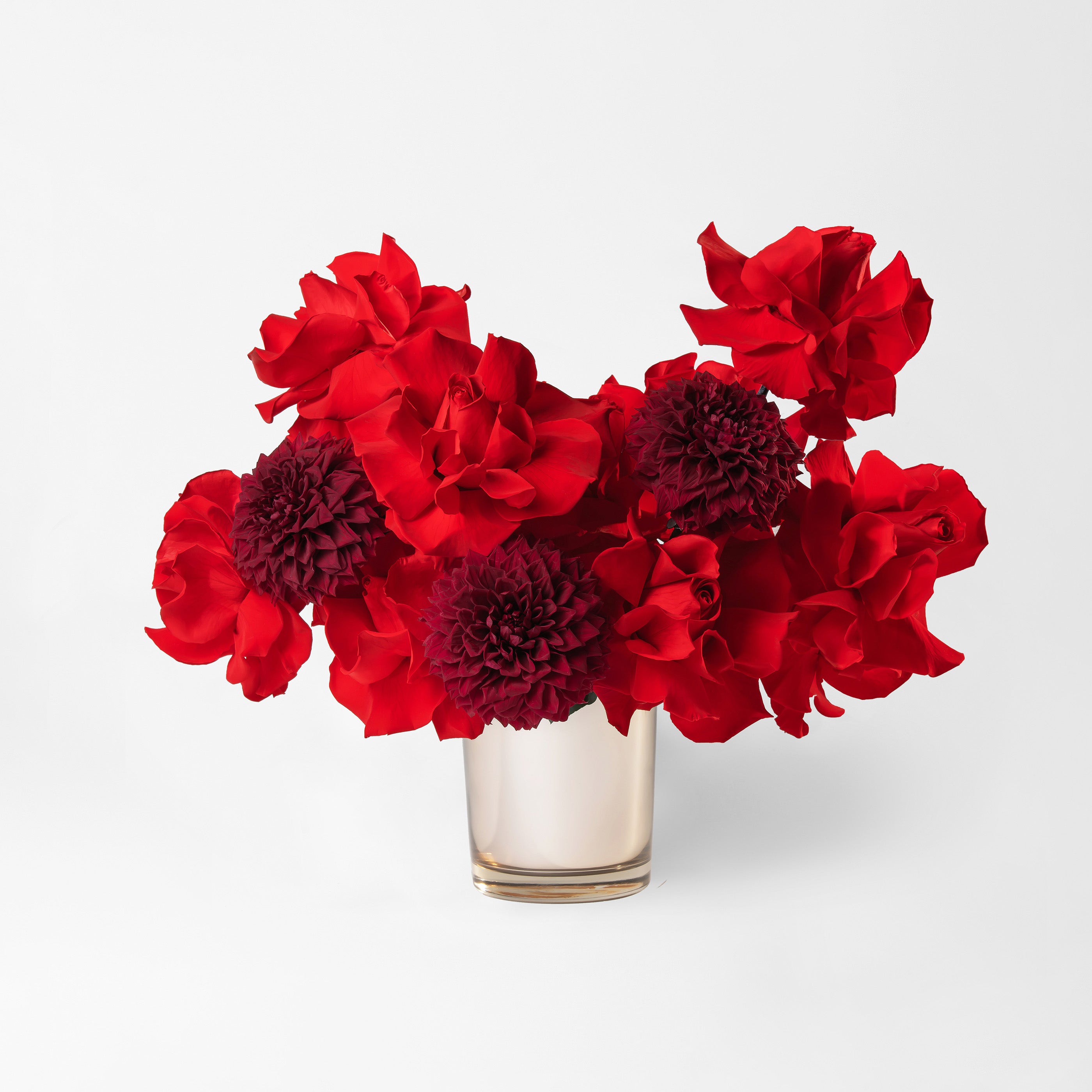 Preserved red reflexed roses and red dahlia in a gold glass vase