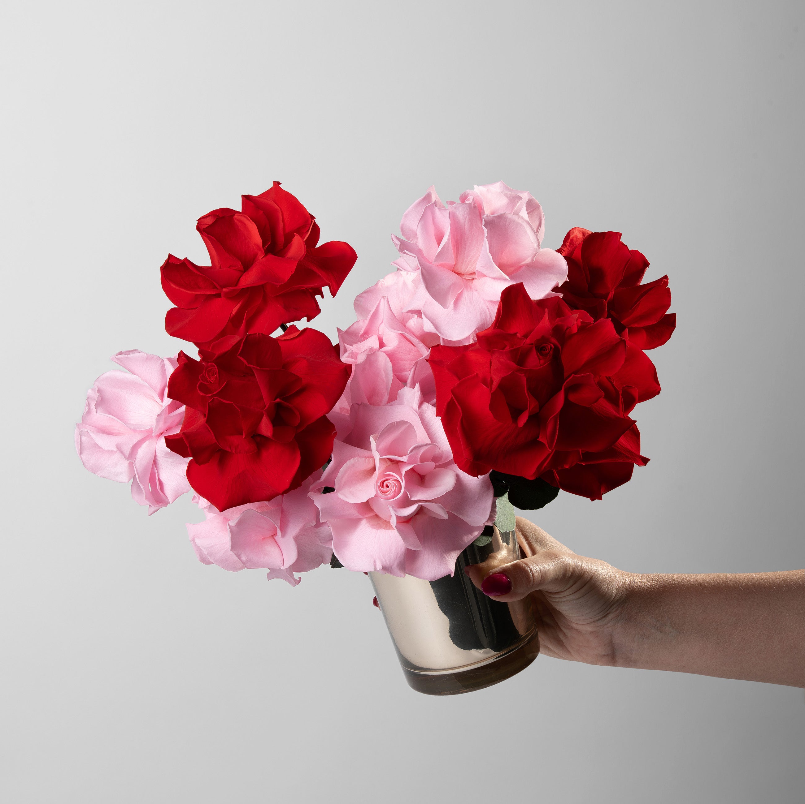 Preserved red and pink reflexed roses in a gold glass vase