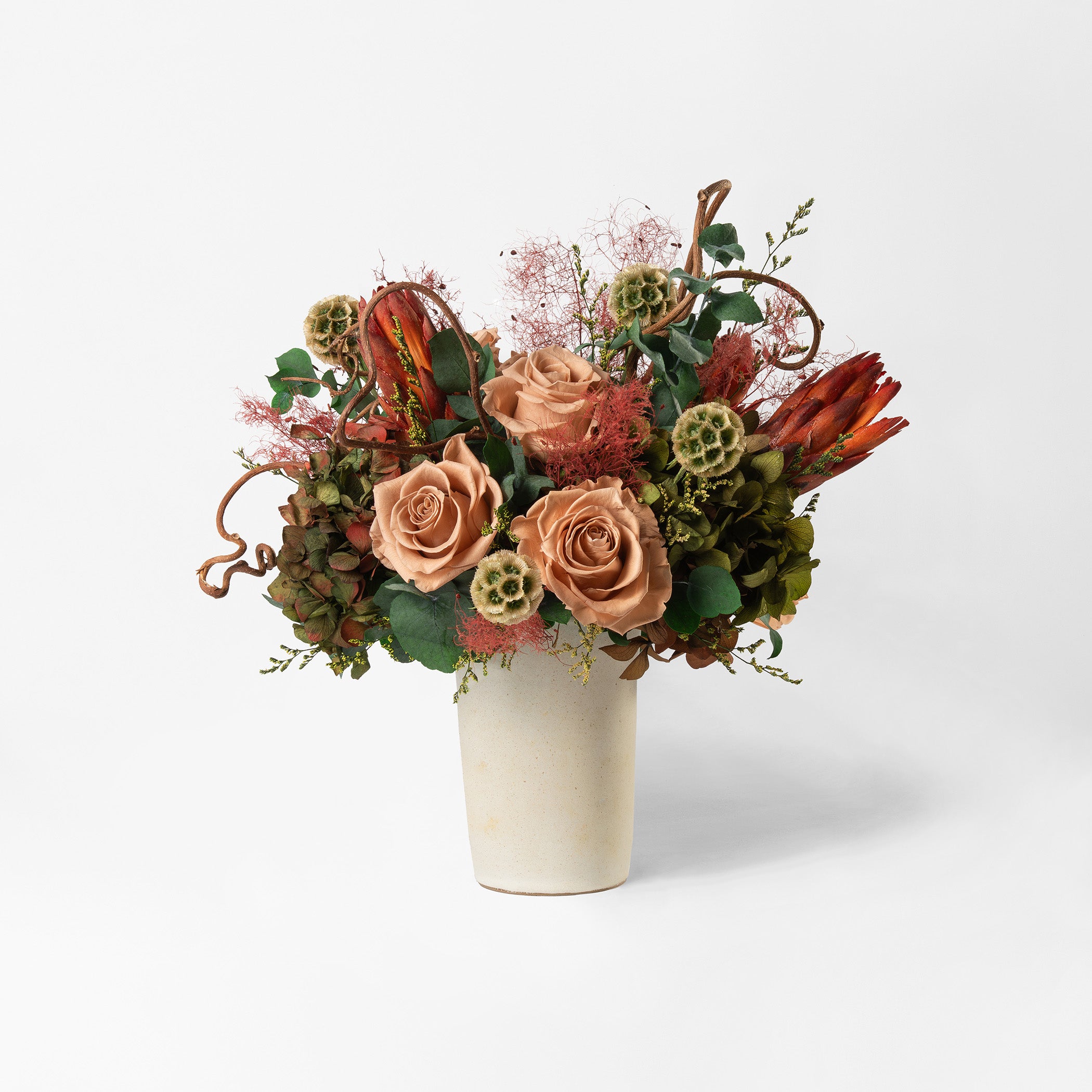 Bouquet of toffee and green mix preserved flowers in a ceramic vase on a white background