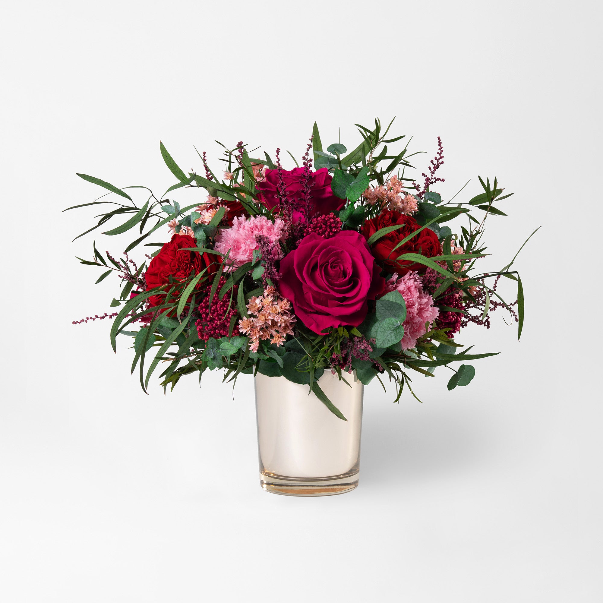 Preserved bouquet of red and pink flowers in a gold glass vase 