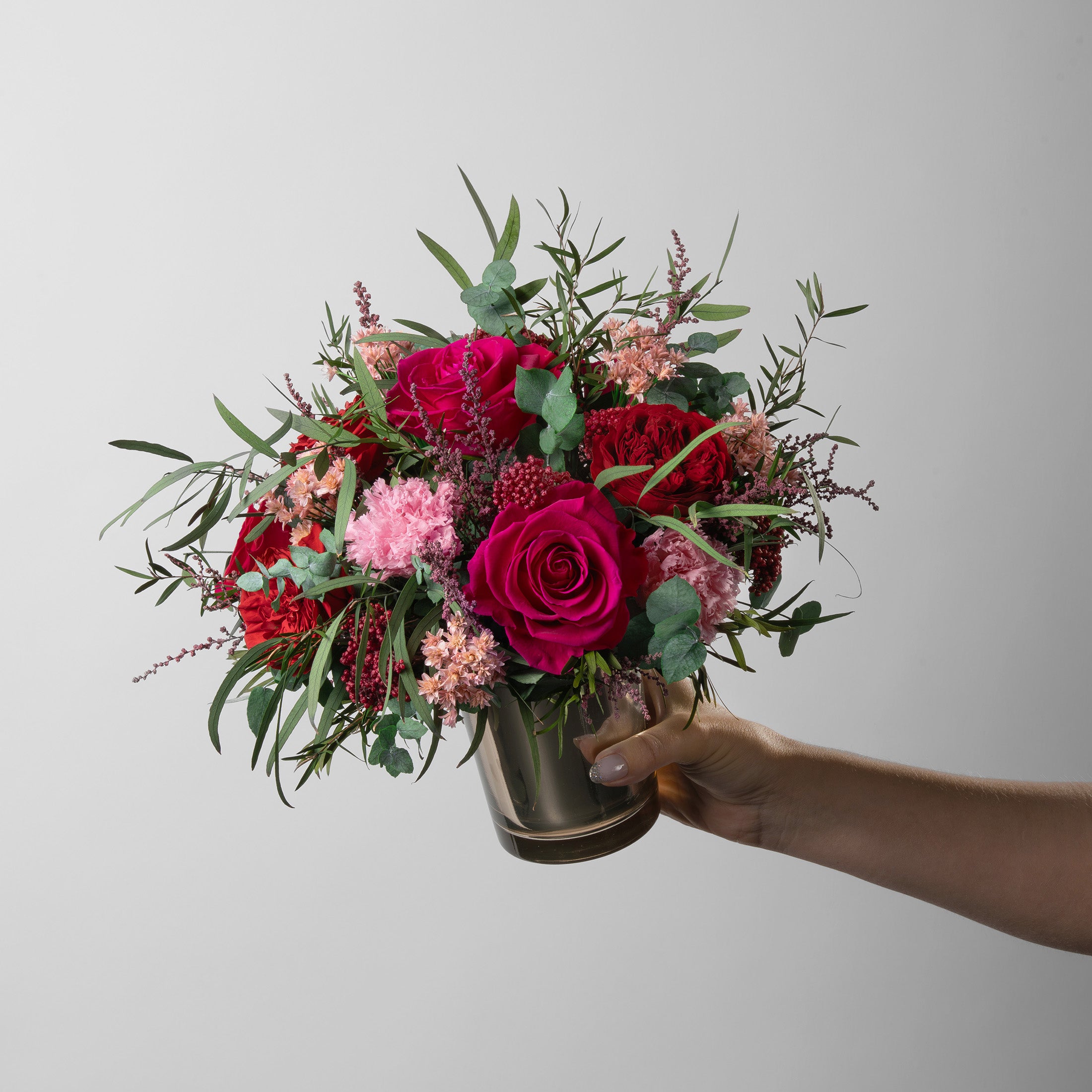 Preserved bouquet of red and pink flowers in a gold glass vase 