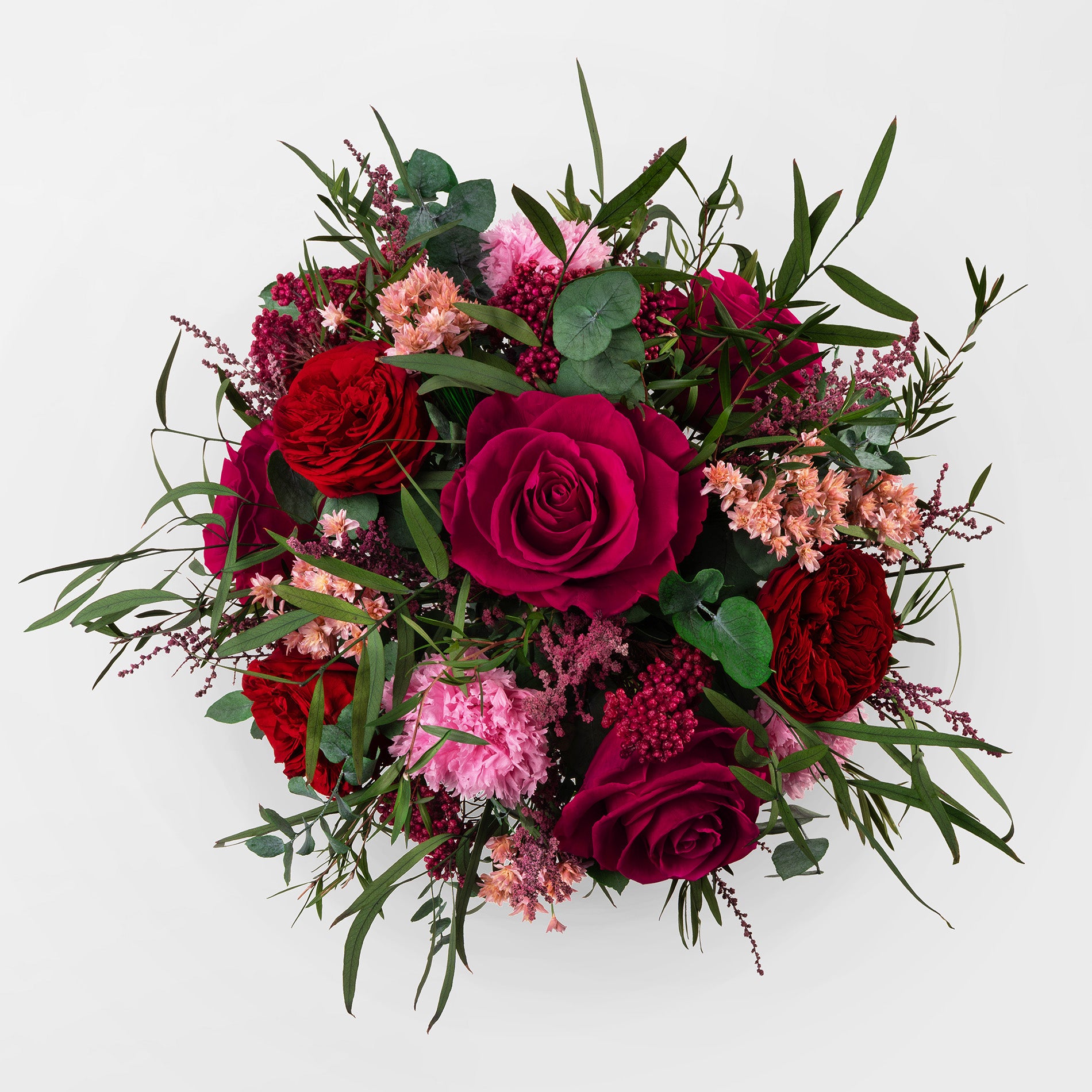Preserved bouquet of red and pink flowers in a gold glass vase 