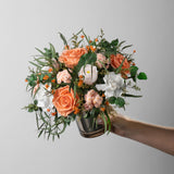 Preserved bouquet of orange and white flowers in a gold glass vase 