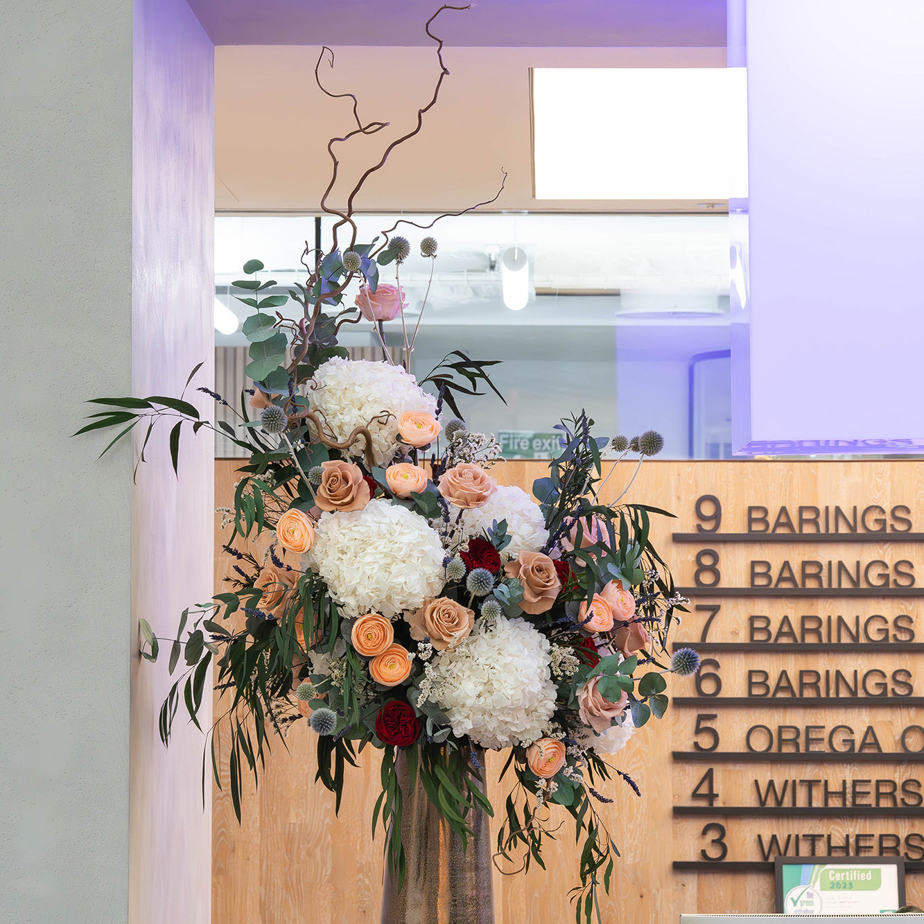 Preserved flower arrangement in a gold vase displayed in a modern office lobby