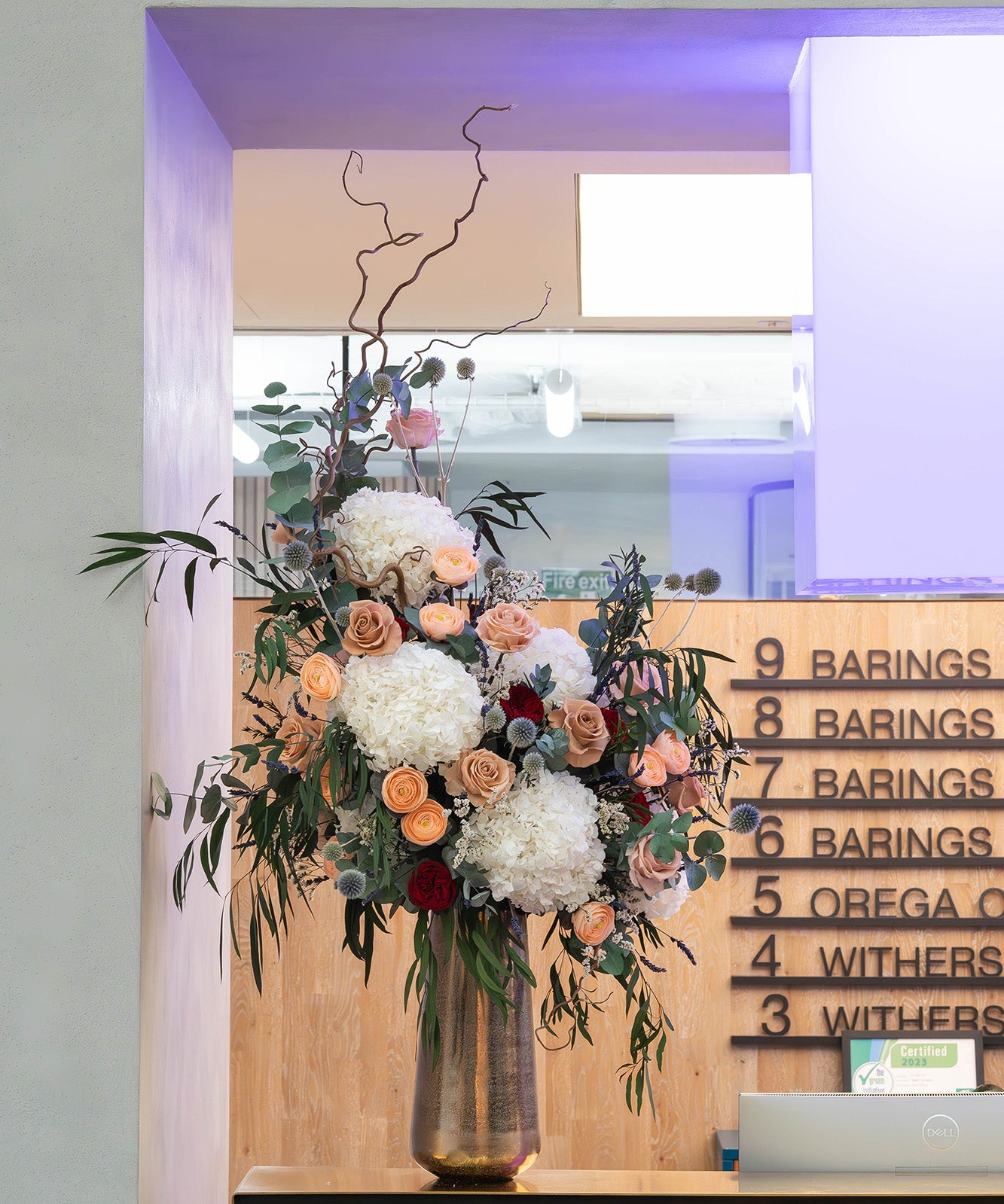 Preserved flower arrangement in a gold vase displayed in a modern office lobby