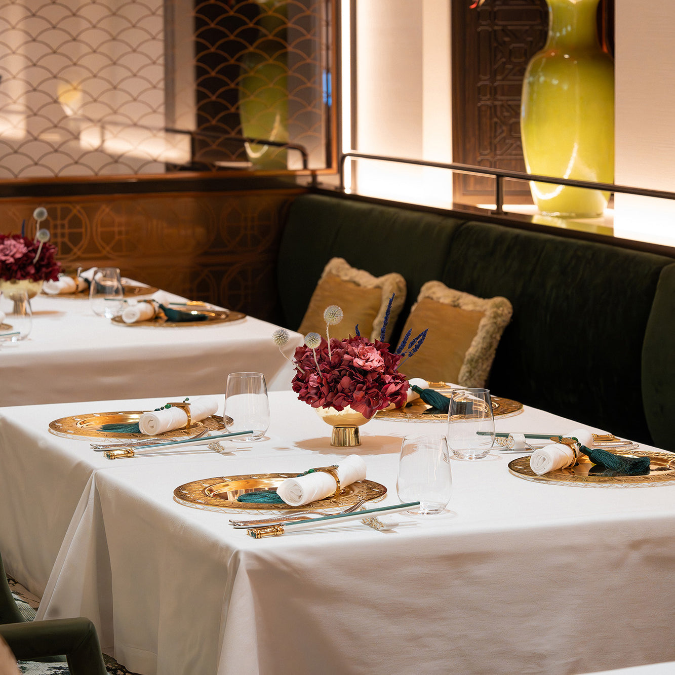 An arrangement of preserved hydrangea, gardenia, and touches of lavender displayed in a metallic vase inside a restaurant