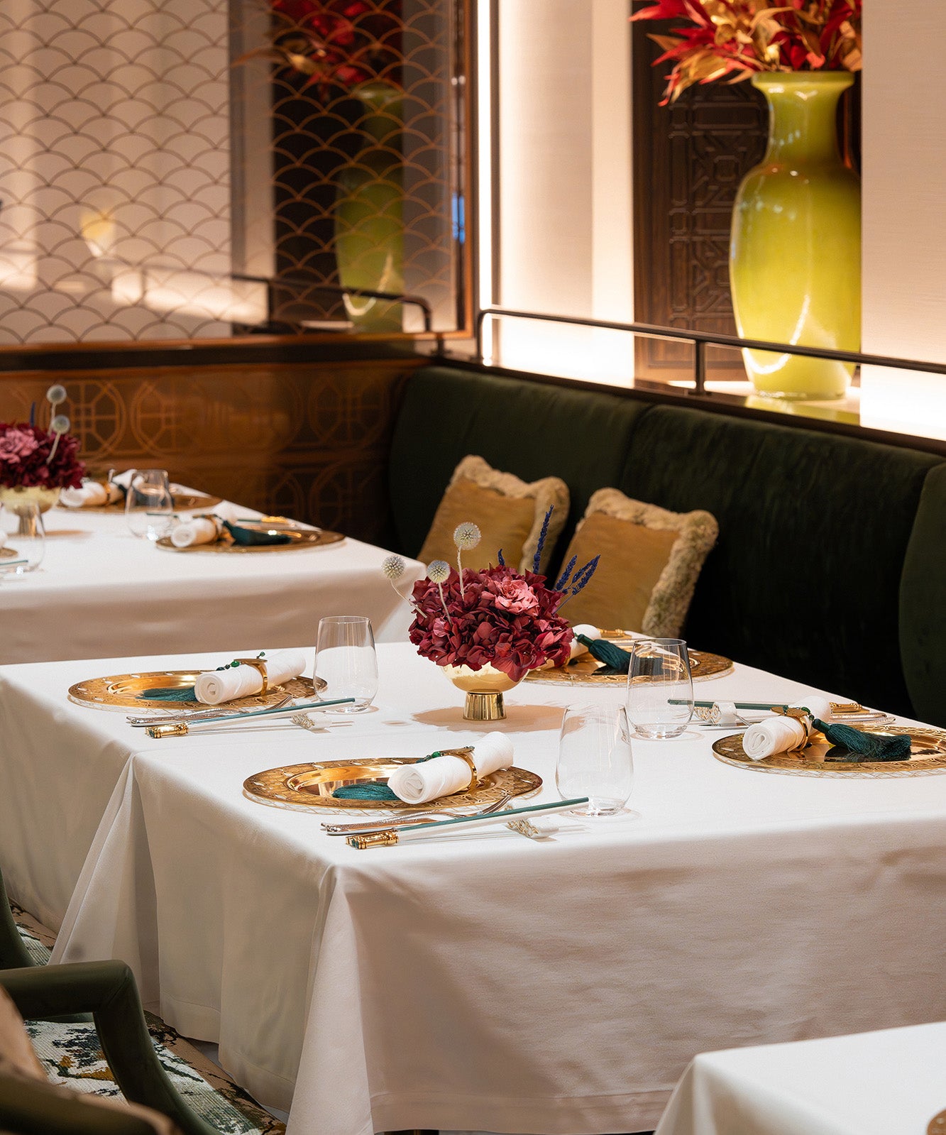 An arrangement of preserved hydrangea, gardenia, and touches of lavender displayed in a metallic vase inside a restaurant