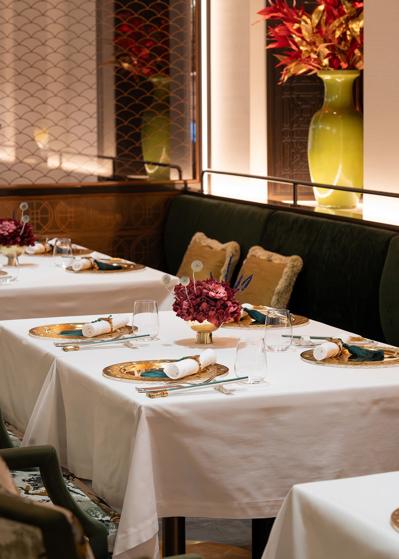 An arrangement of preserved hydrangea, gardenia, and touches of lavender displayed in a metallic vase inside a restaurant
