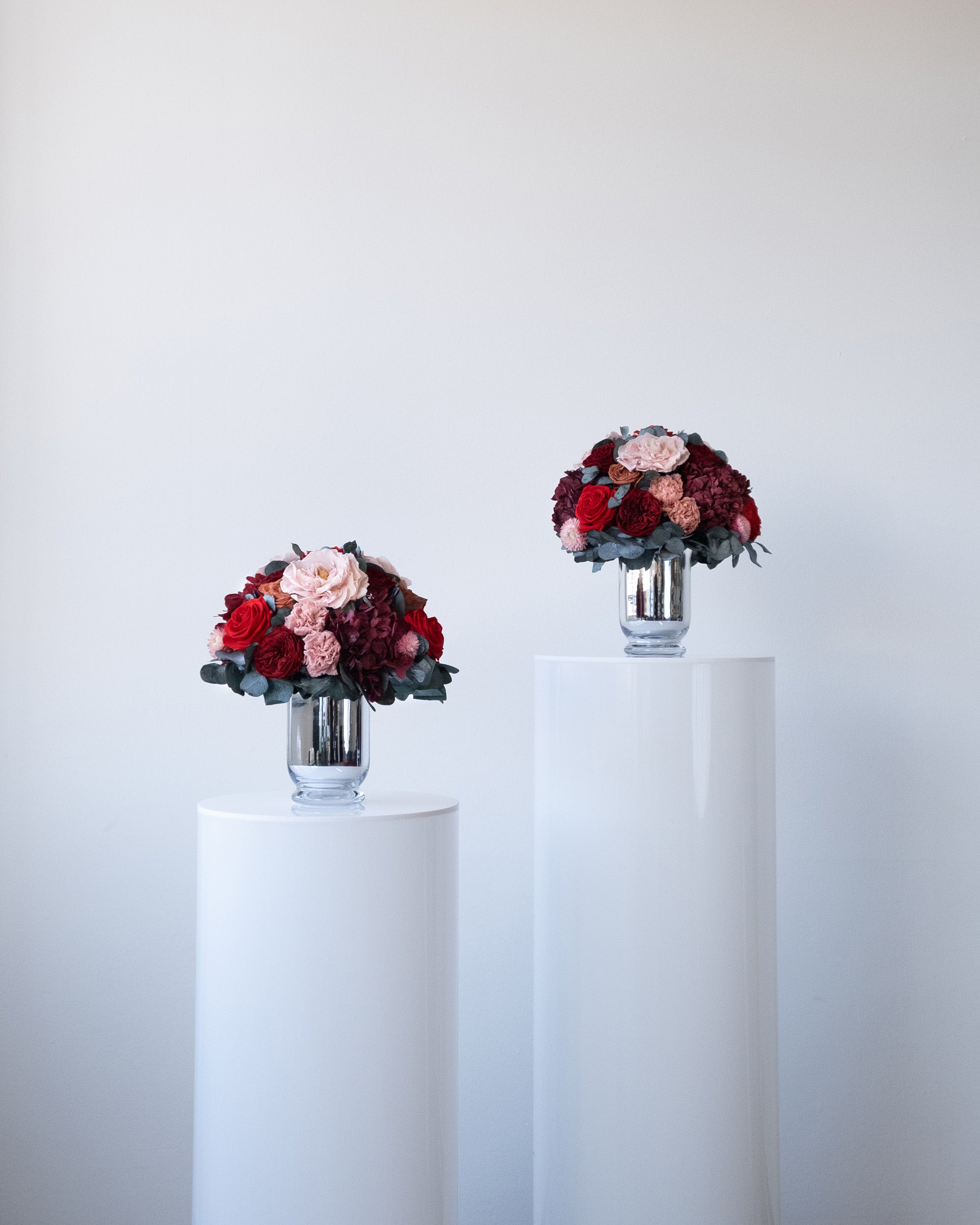 Preserved burgundy and pink mixed flower arrangements in silver vases