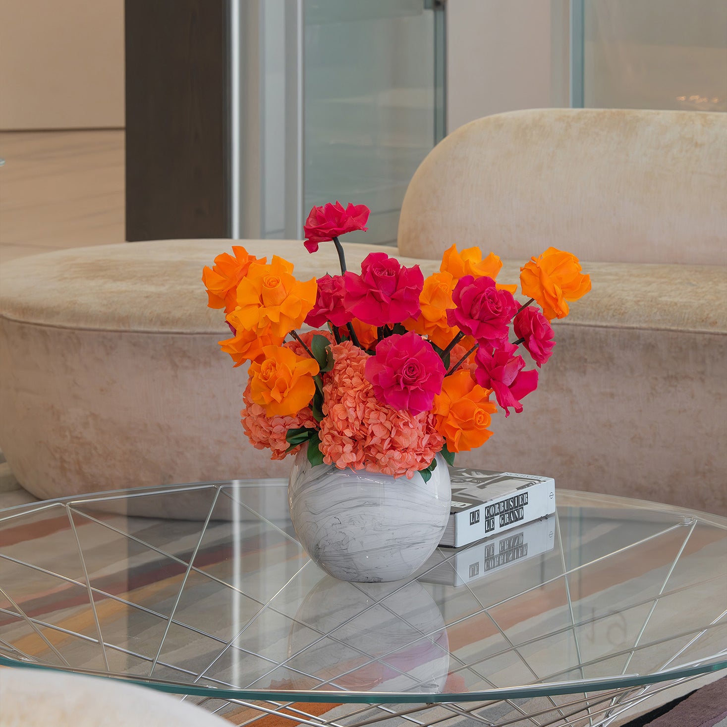 Colourful preserved flower arrangement with reflexed roses and hydrangeas in a marble globe vase on office lobby table