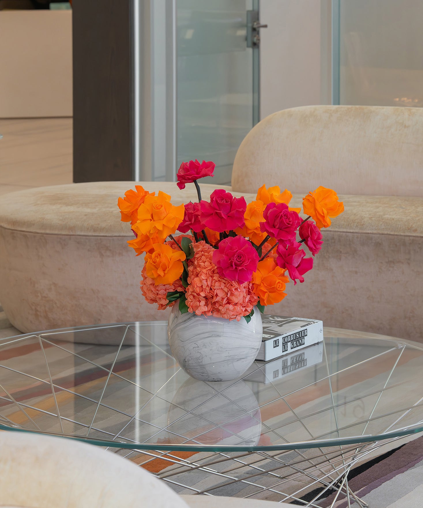 Colourful preserved flower arrangement with reflexed roses and hydrangeas in a marble globe vase on office lobby table