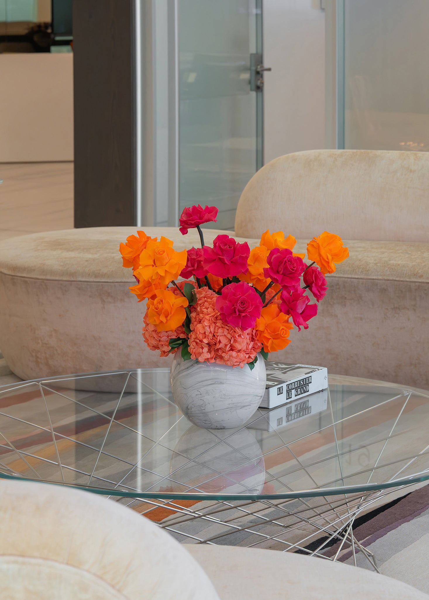 Colourful preserved flower arrangement with reflexed roses and hydrangeas in a marble globe vase on office lobby table