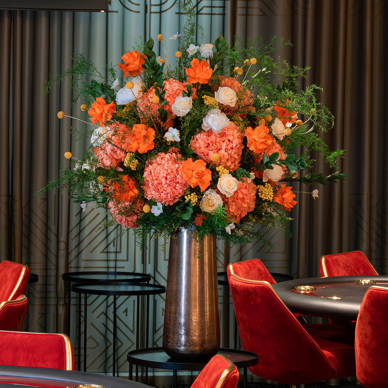 Orange preserved flower arrangement in a metallic vase in a casino.