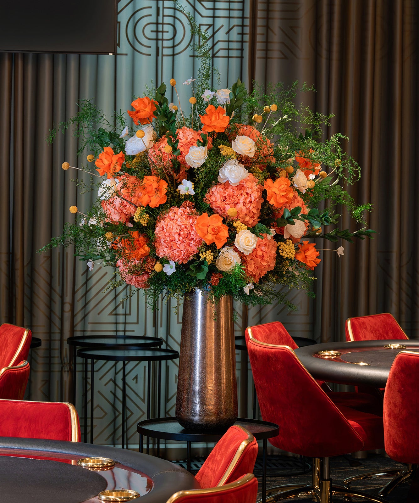 Orange preserved flower arrangement in a metallic vase in a casino.