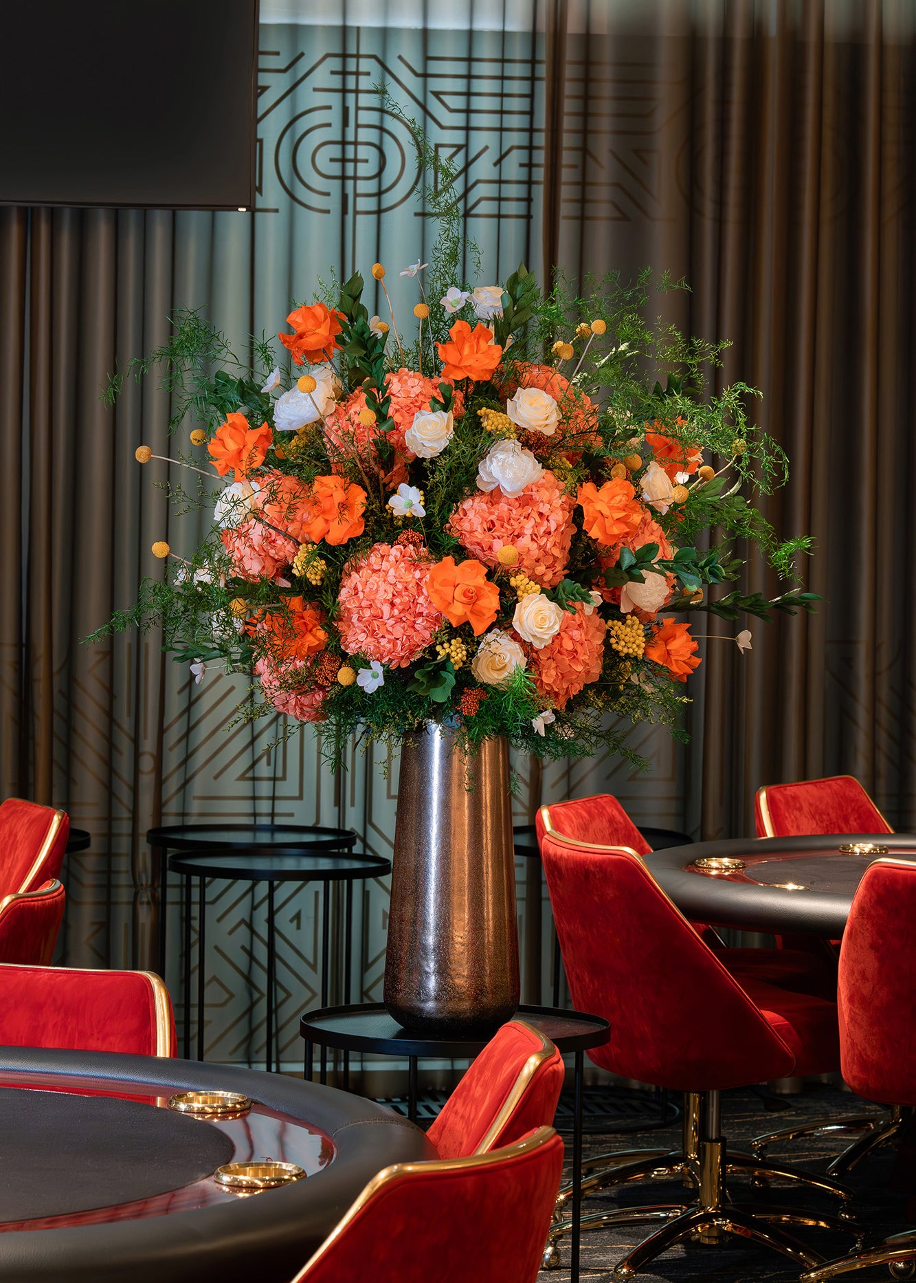 Orange preserved flower arrangement in a metallic vase in a casino.