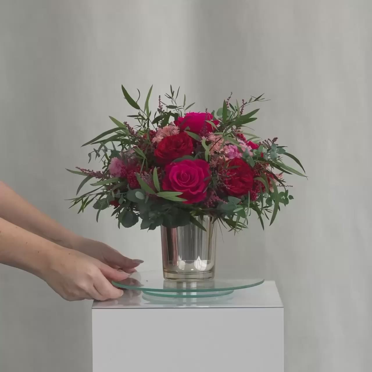 Preserved bouquet of red and pink flowers in a gold glass vase 