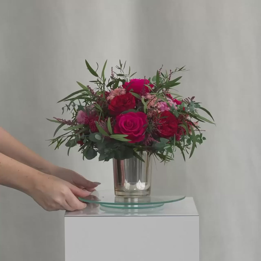 Preserved bouquet of red and pink flowers in a gold glass vase 
